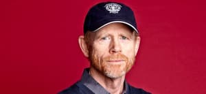 A photo showing Ron Howard sporting a blue sweater over a gray T-shirt and a sports cap to match