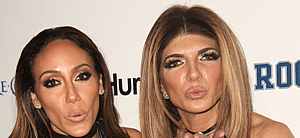 Teresa Giudice and Melissa Gorga posing next to each other and blowing kisses on the red carpet.