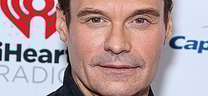 Ryan Seacrest posing for a photo on the red carpet.