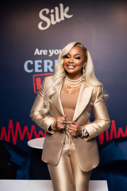 Phaedra Parks posing in a gold suit with blonde hair smiling for a picture.