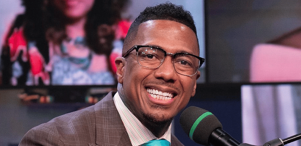 Nick Cannon smiling at a piano