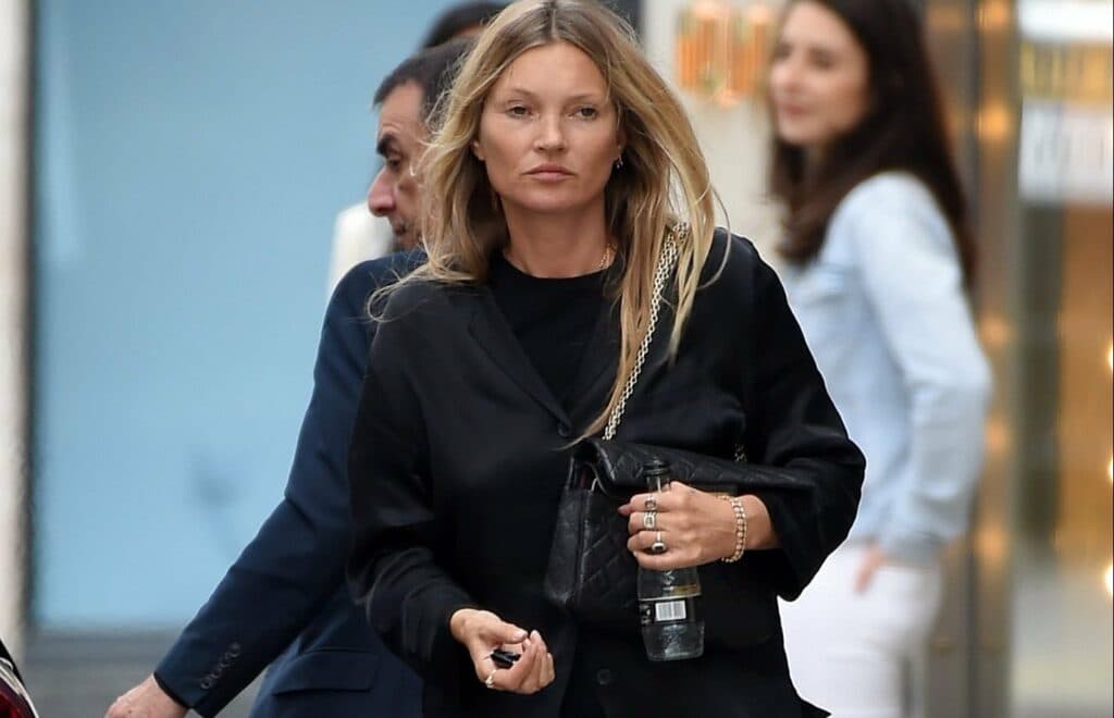 Woman in black blazer walking through corridor with other people in background
