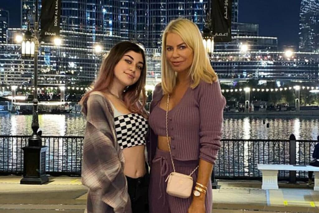 woman and young girl posing in front of water at night