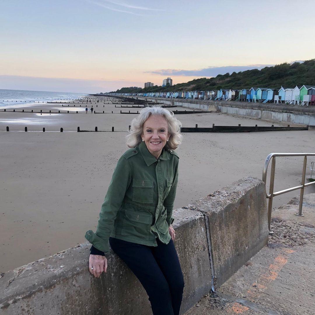 Hayley Mills looks amazing in this green jacket and black pant, by a waterfront.