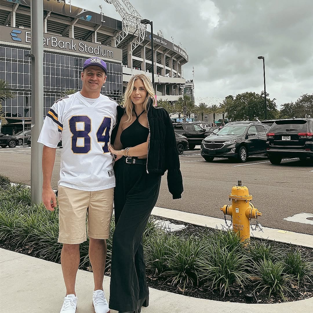 Kayla Reid and Ryan Lochte posing in front of a football stadium.