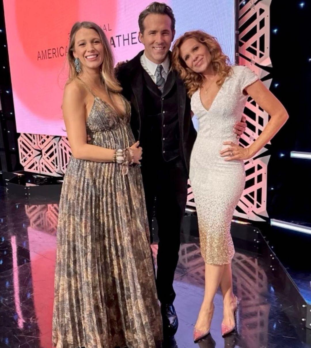 Three people posing together at an event with pink and black geometric backdrop