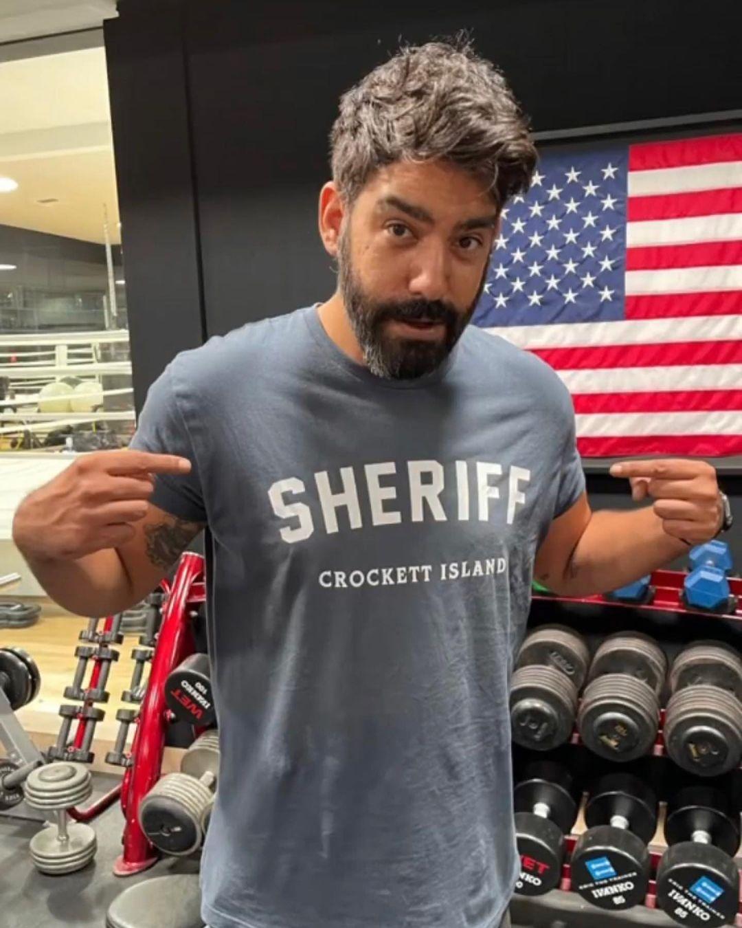 A photo showing Rahul Kohli at the gym sporting a gray shirt.