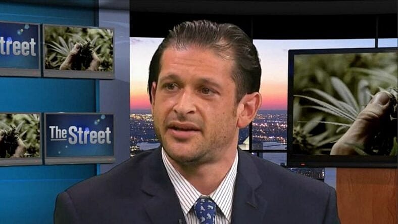 Man in suit being interviewed on tv.