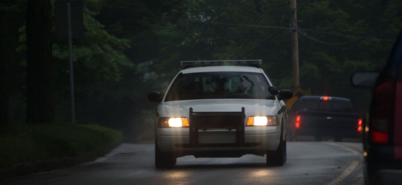 Cop car driving down a dark road