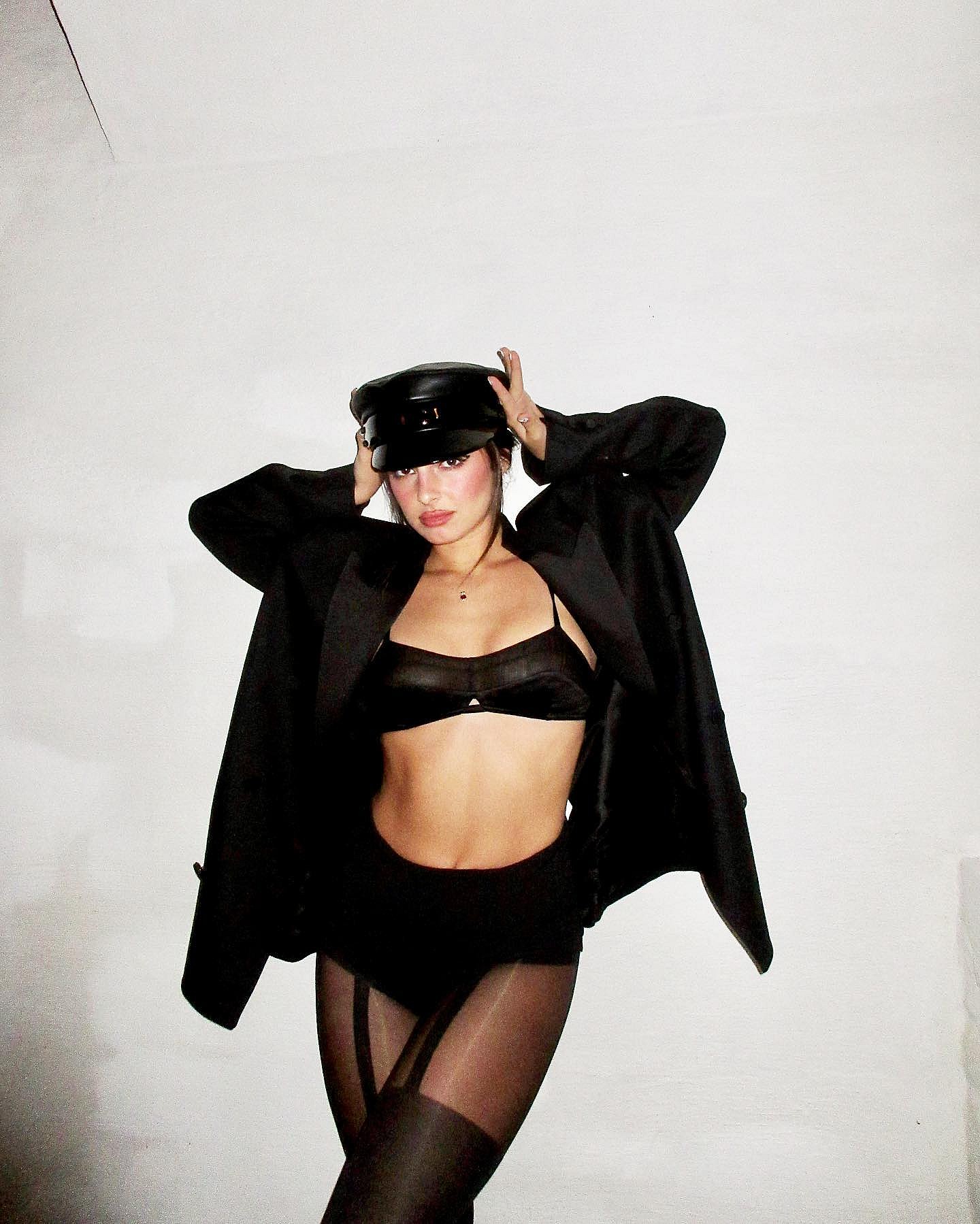 Addison Rae poses in a black bra and heels