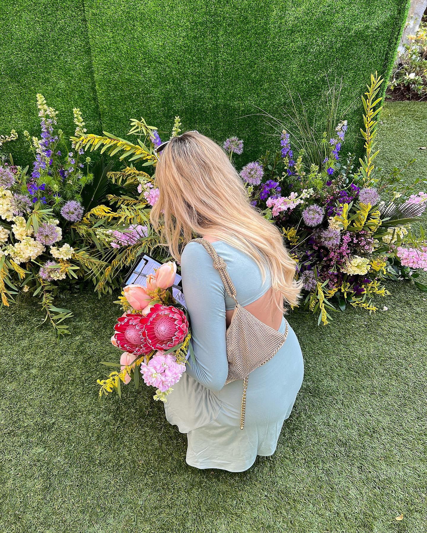Carly Lawrence picks flowers in a green dress