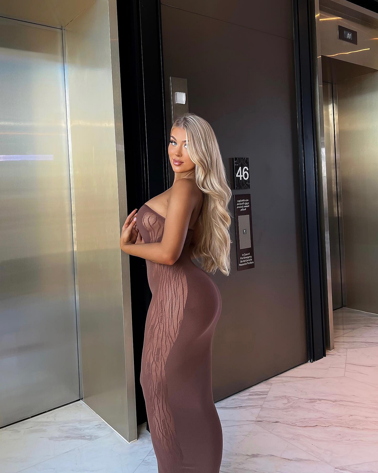 Eve Gale poses in a sheer brown dress