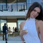 A photo showing Emily Ratajkowski in a white dress holding a glass of champagne