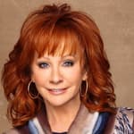 A beautiful photo showing Reba McEntire in a multicolored outfit and her signature curled red hair looks incredible.