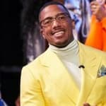 A photo showing Nick Cannon in a yellow color suit paired with a creme turtle neck sweatshirt.