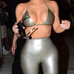 Kim Kardashian wears a silver latex bikini top with matching leggings as she and sister Khloe Kardashian arrive to her Skims pop-up event in Miami