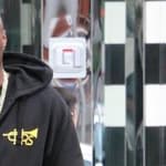 Lamar Odom wearing a black hoodie with gold cross design and chain necklace
