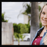 Jinger Duggar smiling outdoors in a denim shirt and red top