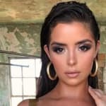 Demi Rose poses for the camera in a gold one-piece.