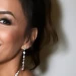 Eva Longoria smiles by a wall