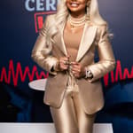 Phaedra Parks posing in a gold suit with blonde hair smiling for a picture.