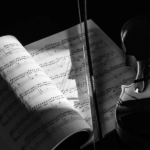 Black and white photo of violin and sheet music.