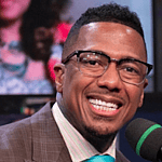 Nick Cannon smiling at a piano