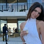 A photo showing Emily Ratajkowski in a white dress holding a glass of champagne