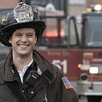 A photo showing Jesse Spencer in his fireman gear with a smile on his face.