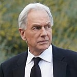 An amazing photo of Mark Harmon sporting a black suit with a white T-shirt and black tie.