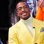A photo showing Nick Cannon in a yellow color suit paired with a creme turtle neck sweatshirt.