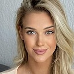 Veronika Rajek smiles to the camera while wearing a cream top with long sleeves.