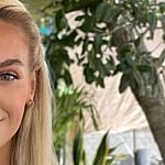 Veronika Rajek in a plunging white crop top smiles to the camera.