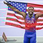 Noah Lyles celebrating at the 2024 Paris Olympics with American Flag