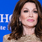 Lisa Vanderpump posing in a gold dress on the red carpet.