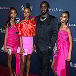 Diddy posing with his daughters on the red carpet.