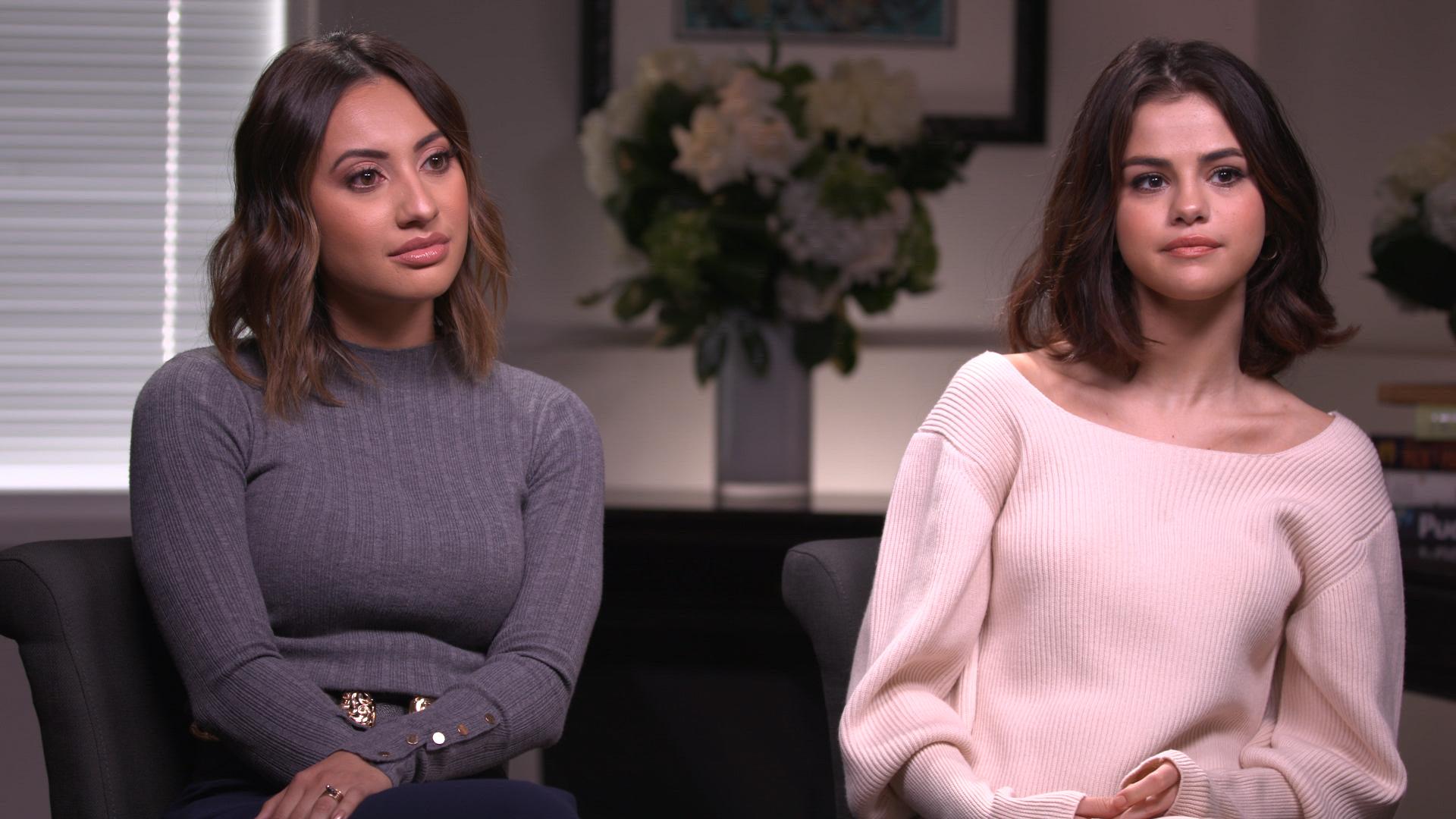 Two women sitting on a couch in an indoor setting during an interview or talk show appearance