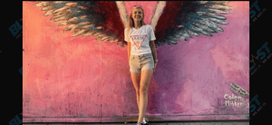 Woman posing in front of colorful wing mural