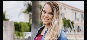 Jinger Duggar smiling outdoors in a denim shirt and red top