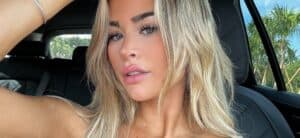 Emily Elizabeth takes a selfie inside the car while wearing a low-cut black top.
