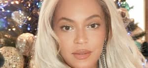 Beyonce poses by a Christmas tree