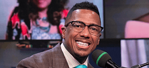 Nick Cannon smiling at a piano