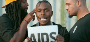 DaBaby holding up a sign that says AIDS