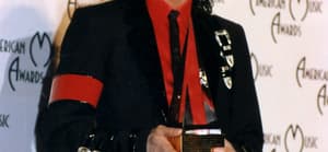 A photo showing Michael Jackson in his signature black suit paired with a red inner T-shirt at an event.