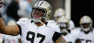 NFL player wearing New Orleans Saints uniform and helmet with arm raised