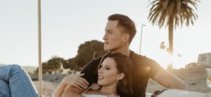 Katie Thurston and John Hersey relax around palm trees