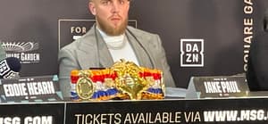 Jake Paul looks out at the media as he promotes the Taylor vs Serrano boxing event as his girlfriend sits in crowd nearby in NYC