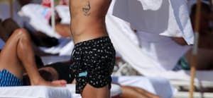 Shirtless DJ Diplo does some awkward looking exercises in the sand before chatting up billionaire developer Alan Faena on the beach in Miami