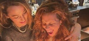 Blake Lively and her sister smiling together at an indoor celebration