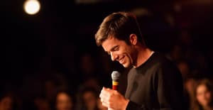 A photo showing John Mulaney telling jokes to a vast audience